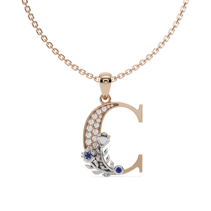 A hand-crafted rose gold letter C pendant, entwined with a white gold floral vine featuring pavé diamonds and a vivid gem quality blue sapphire colour stone.