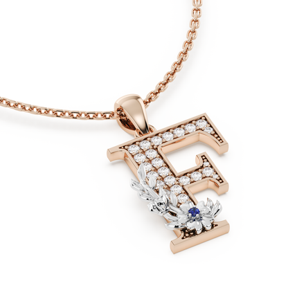 Handcrafted white gold letter F initial pendant from the Everbloom collection, set with diamonds and a rose gold floral motif featuring a round Blue sapphire gemstone.
